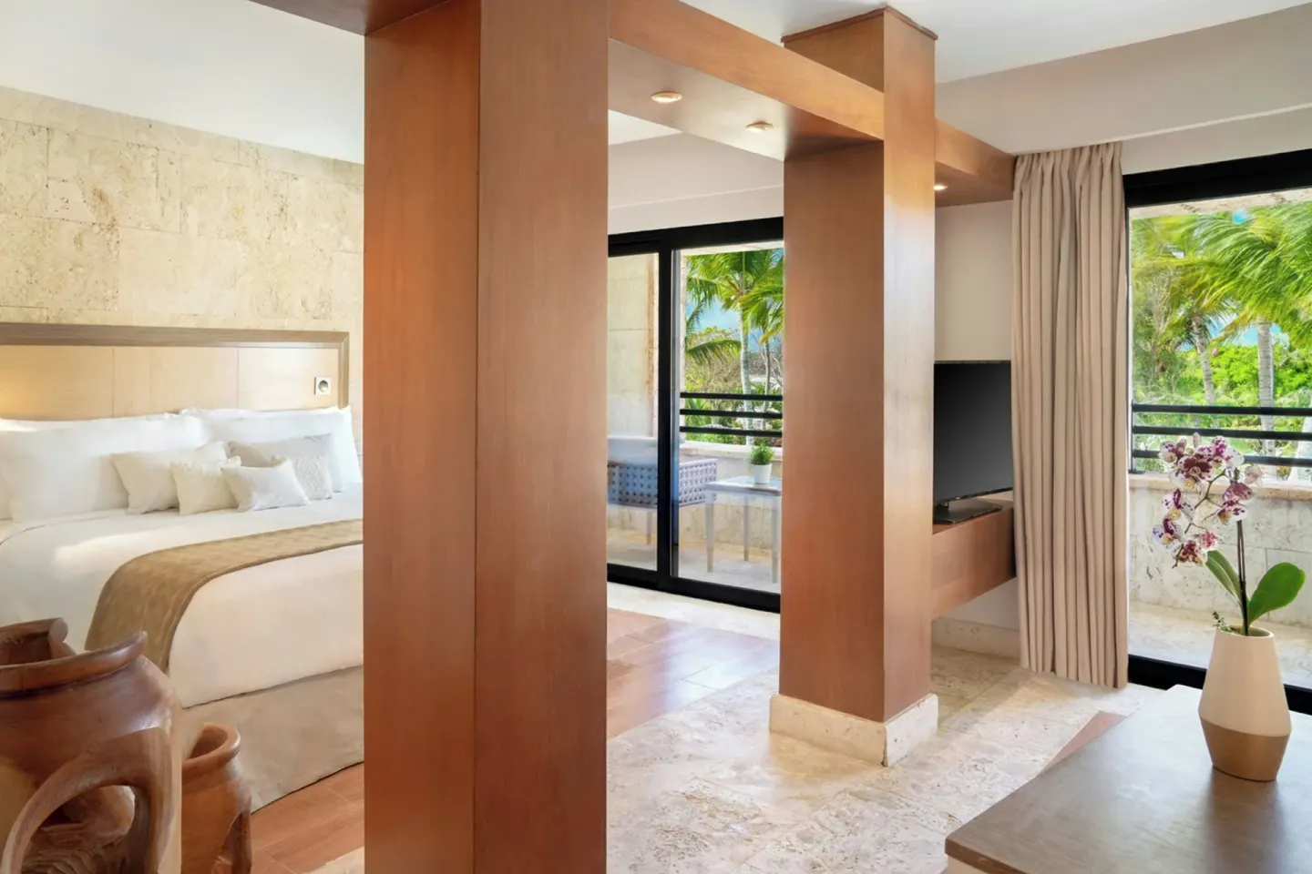 Junior Suite Balcony Garden View interior with king bed and TV at Sanctuary Cap Cana, a Luxury Collection Resort.