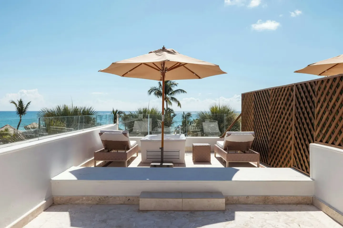 Junior Suite ocean-view balcony at Sanctuary Cap Cana, a Luxury Collection Resort with loungers, umbrellas, and sea beyond.