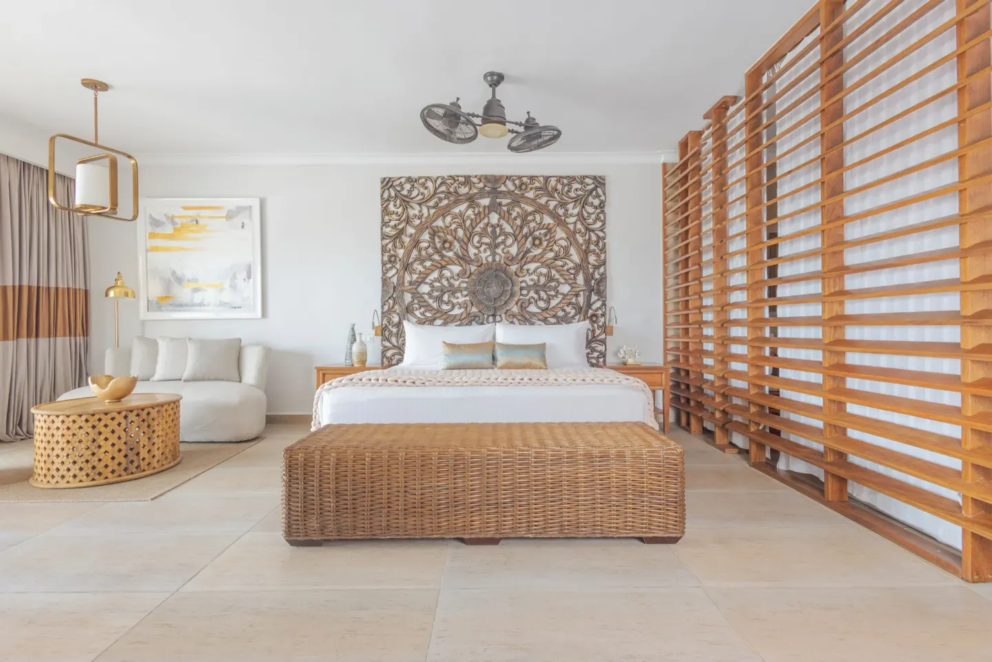 Junior Suite king bed at Sanctuary Cap Cana, a Luxury Collection Resort with carved headboard, lounge chair, and wood screen.
