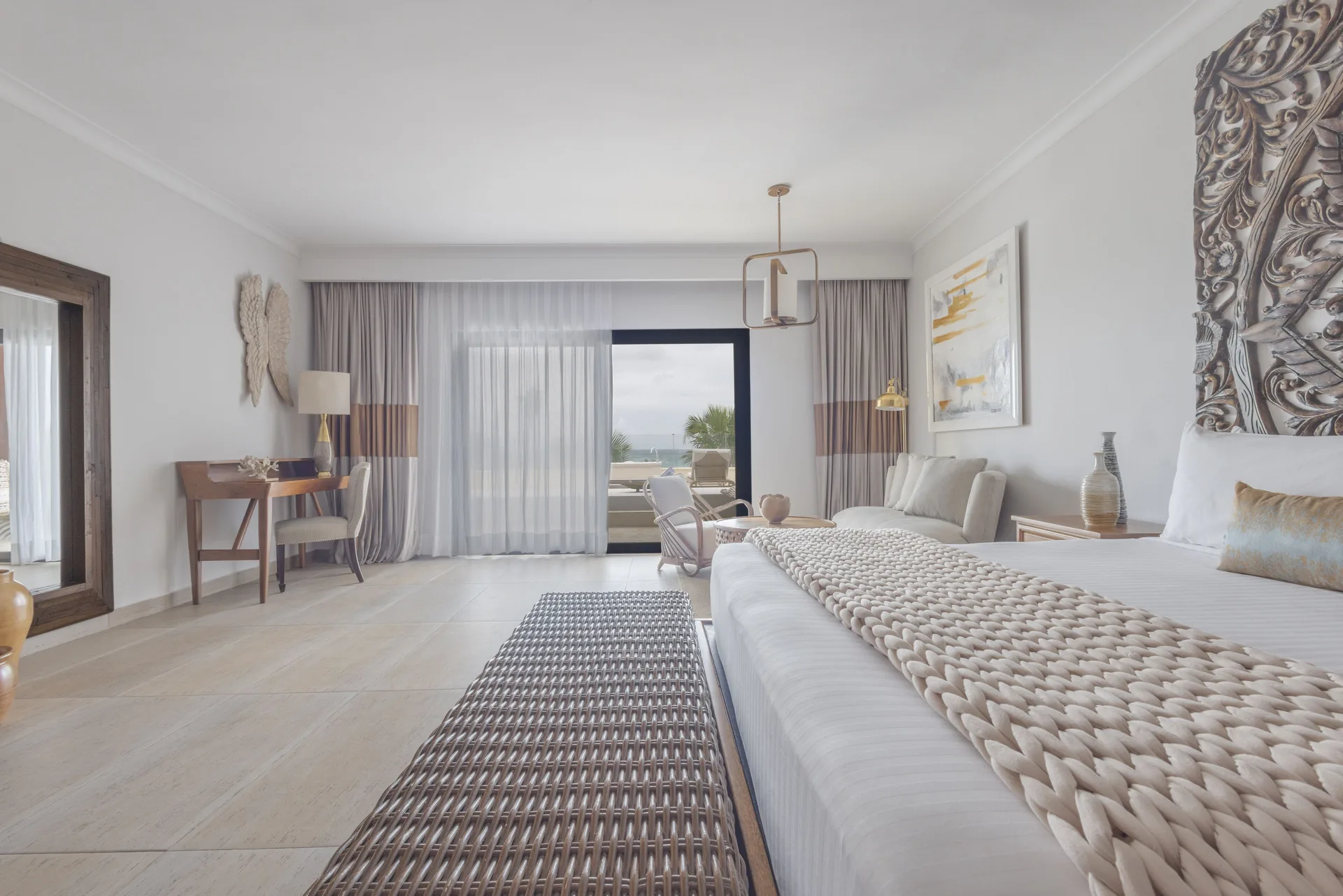 Junior Suite ocean view king bedroom at Sanctuary Cap Cana, a Luxury Collection Resort with balcony doors and sitting area.