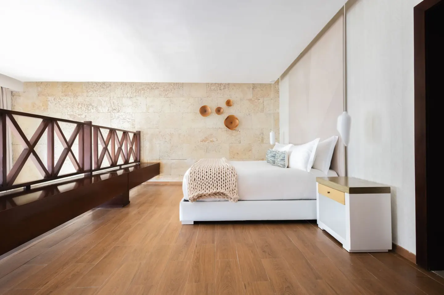 Loft sleeping area with a bed and wood railing in a suite at Sanctuary Cap Cana, a Luxury Collection Resort.