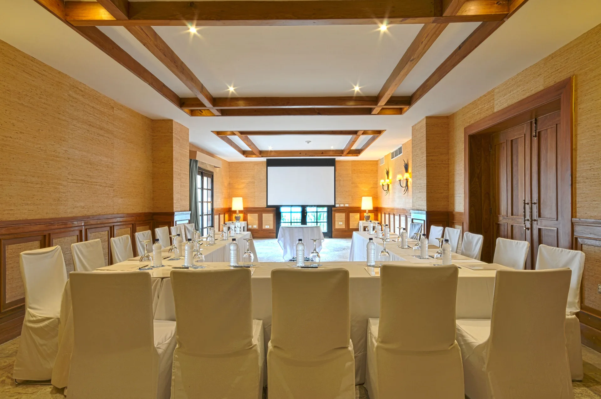 Meeting room with U-shaped tables and a projection screen at Sanctuary Cap Cana, a Luxury Collection Resort.