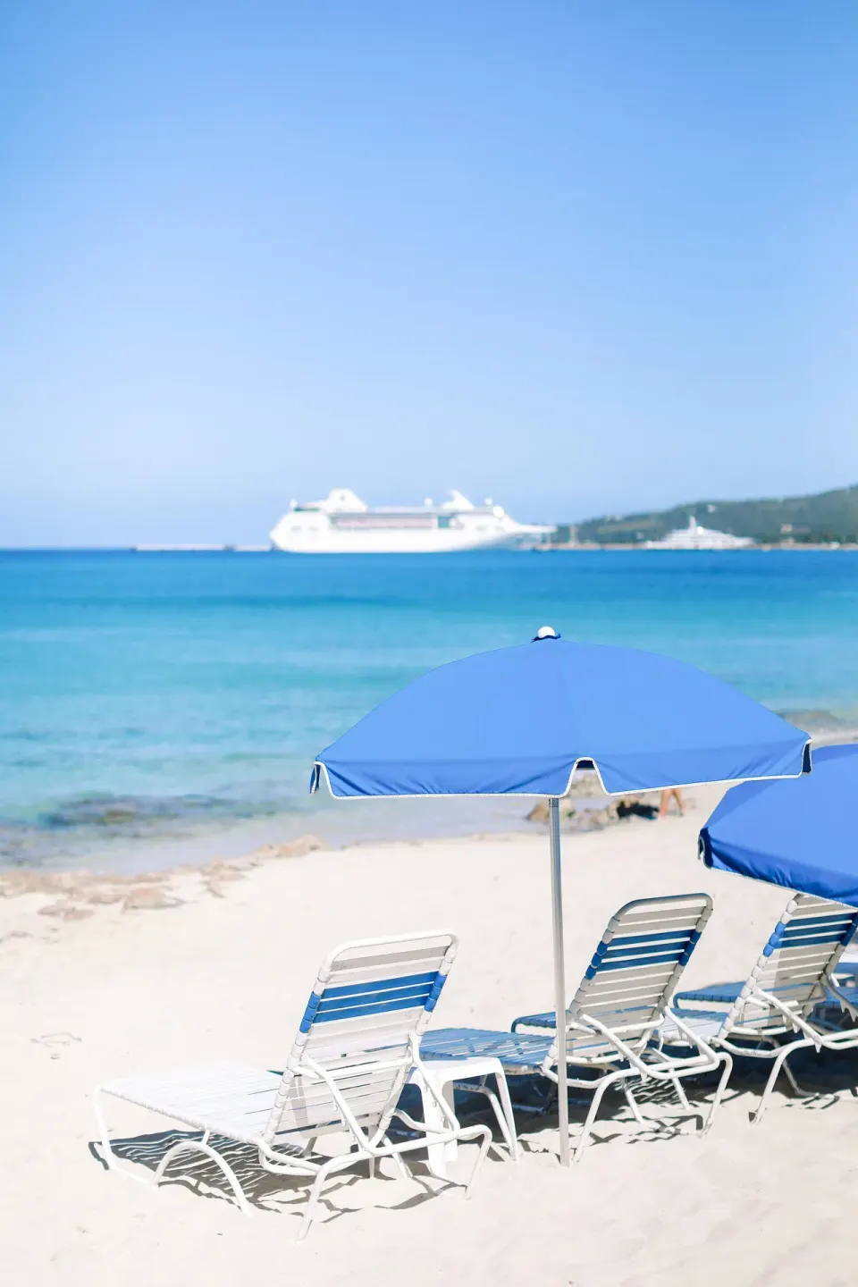 Blue beach umbrellas and lounge chairs by the water at Sand Castle on the Beach.