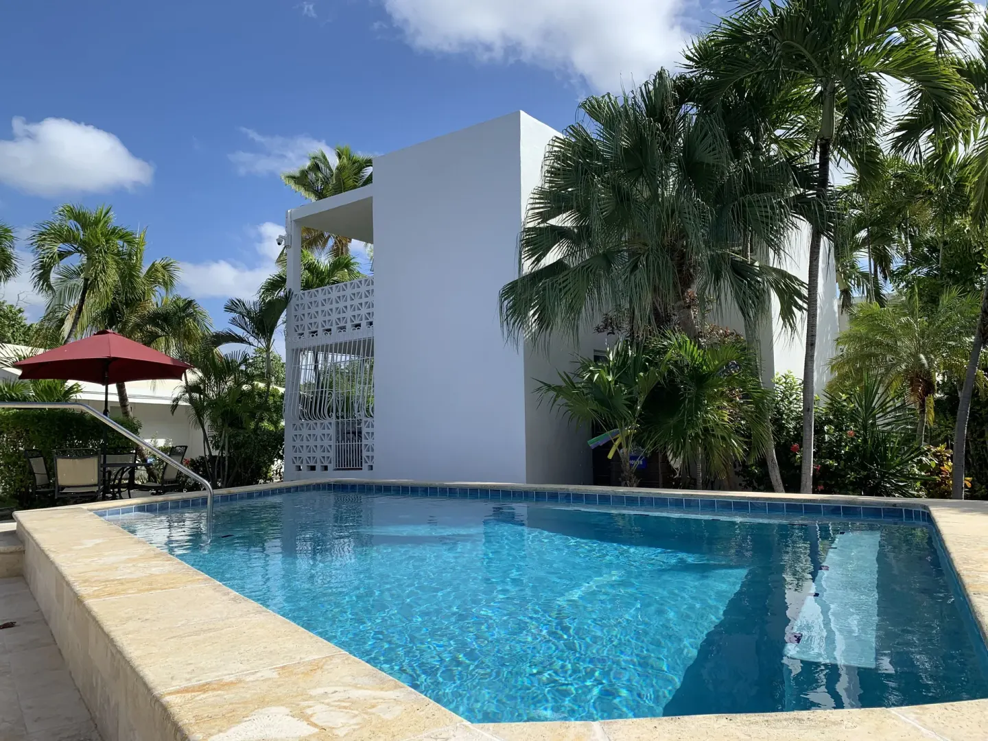 Quiet courtyard pool with palms and white resort building at Sand Castle on the Beach.