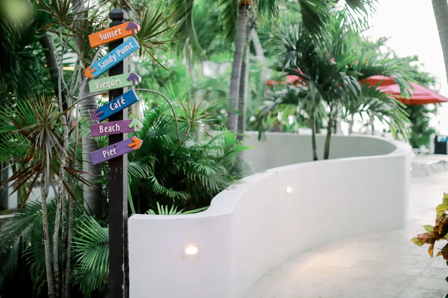 Colorful wayfinding signs beside a curved garden path at Sand Castle on the Beach.