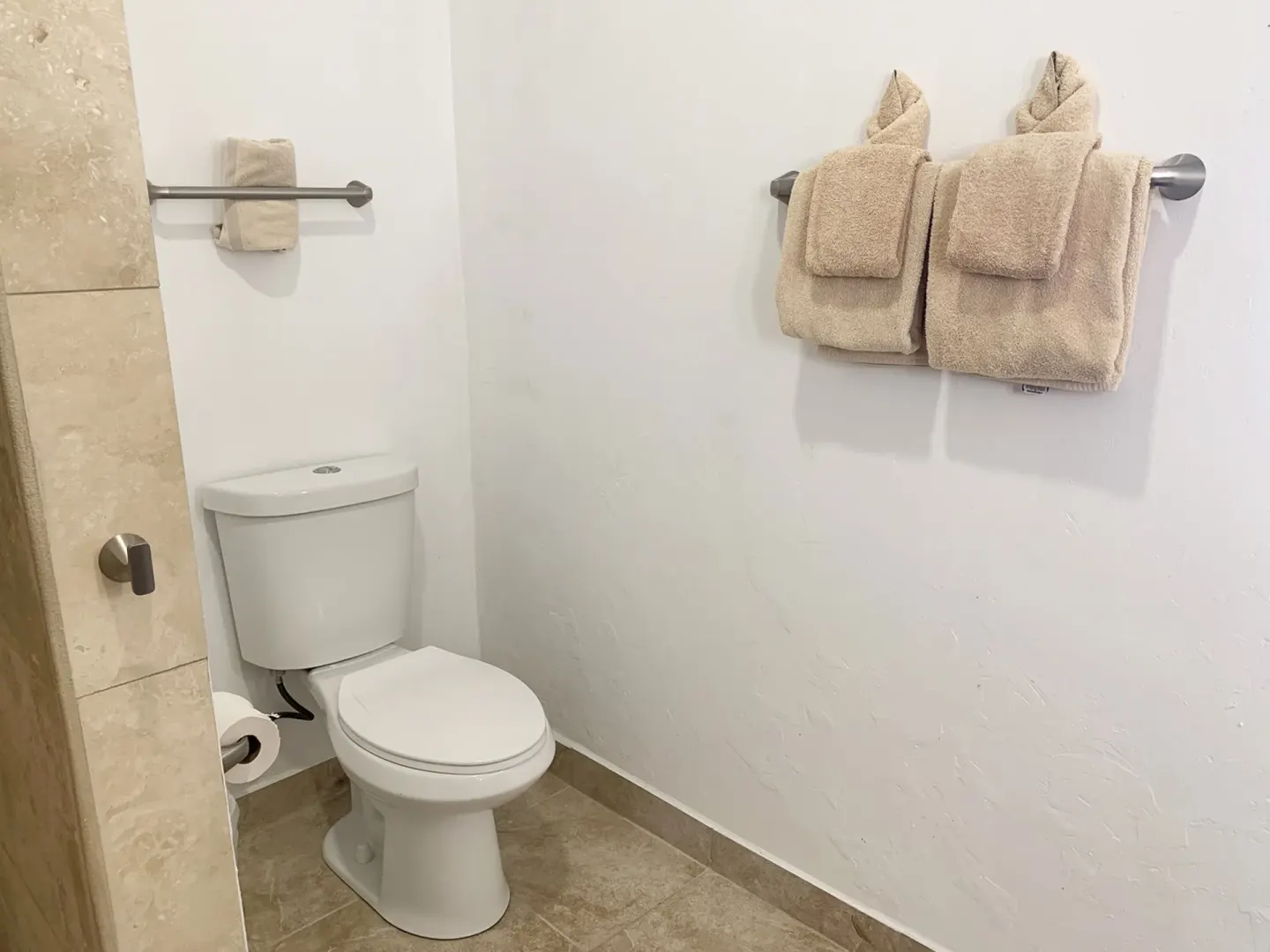 Guest bathroom toilet area with folded towels at Sand Castle on the Beach.