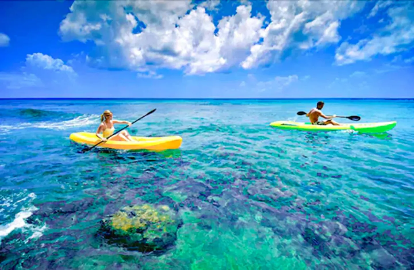 Two kayakers paddle over clear turquoise water near Sand Castle on the Beach.