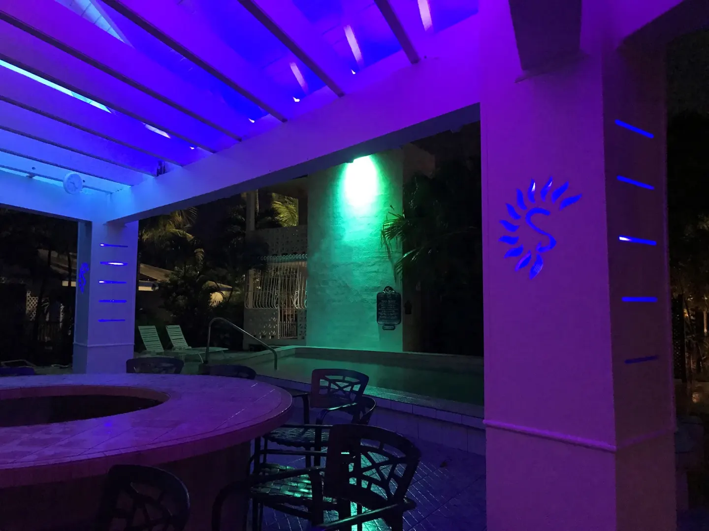 Pool area at night with purple and green lighting at Sand Castle on the Beach.