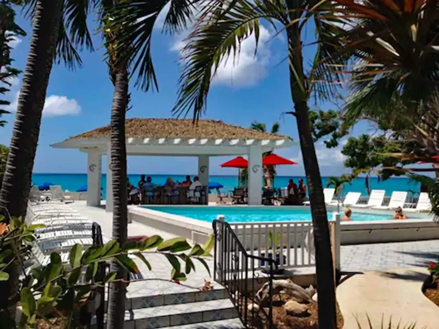Poolside pavilion and ocean view framed by palms at Sand Castle on the Beach.