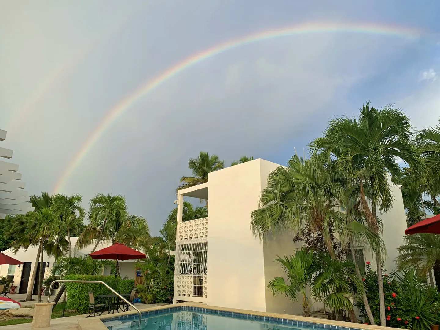 Rainbow over the courtyard pool and palms at Sand Castle on the Beach.