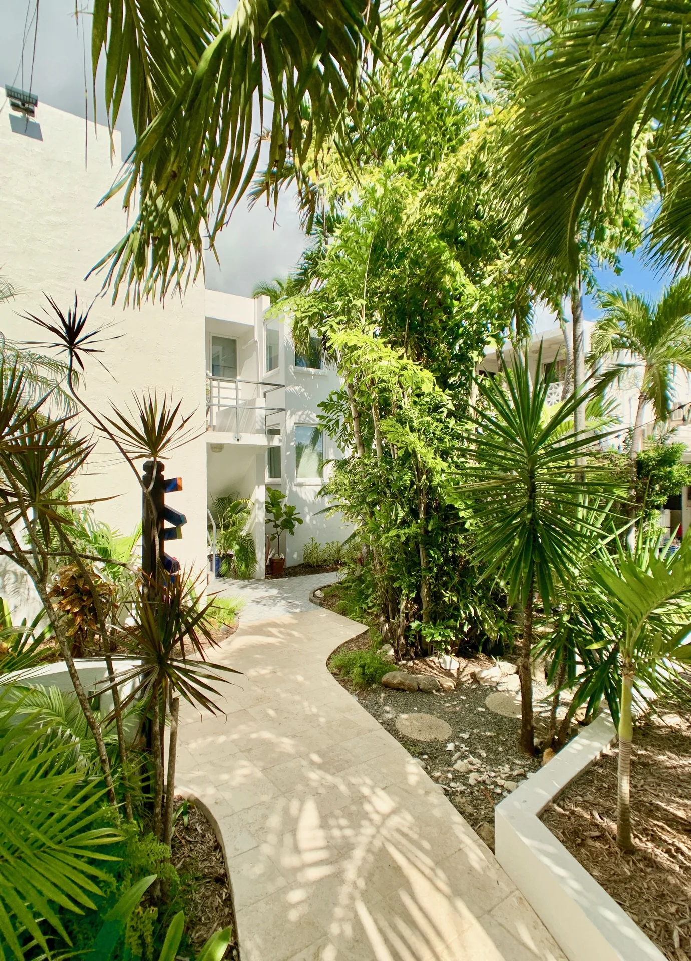 Tropical garden walkway beside white guest buildings at Sand Castle on the Beach.