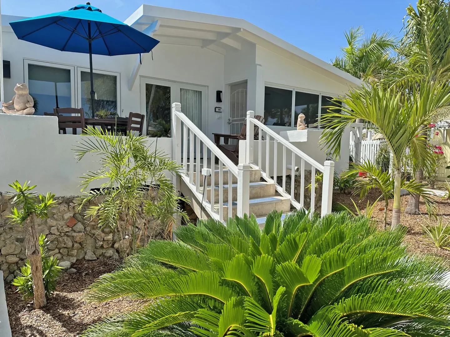 Dolphin Villa exterior with patio umbrella and tropical landscaping at Sand Castle on the Beach.