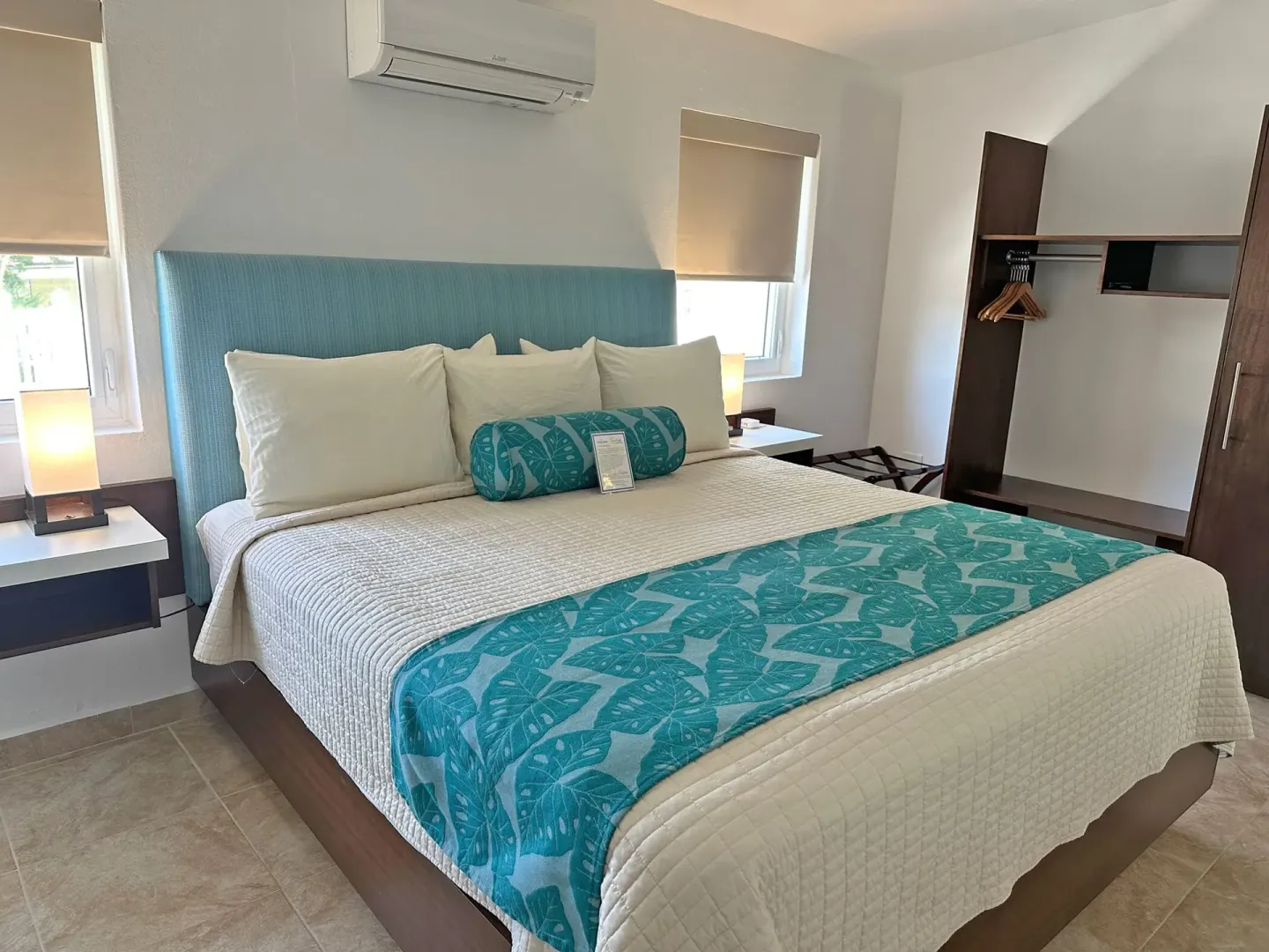 Dolphin Villa king bedroom at Sand Castle on the Beach with bedside lamps and open closet storage.