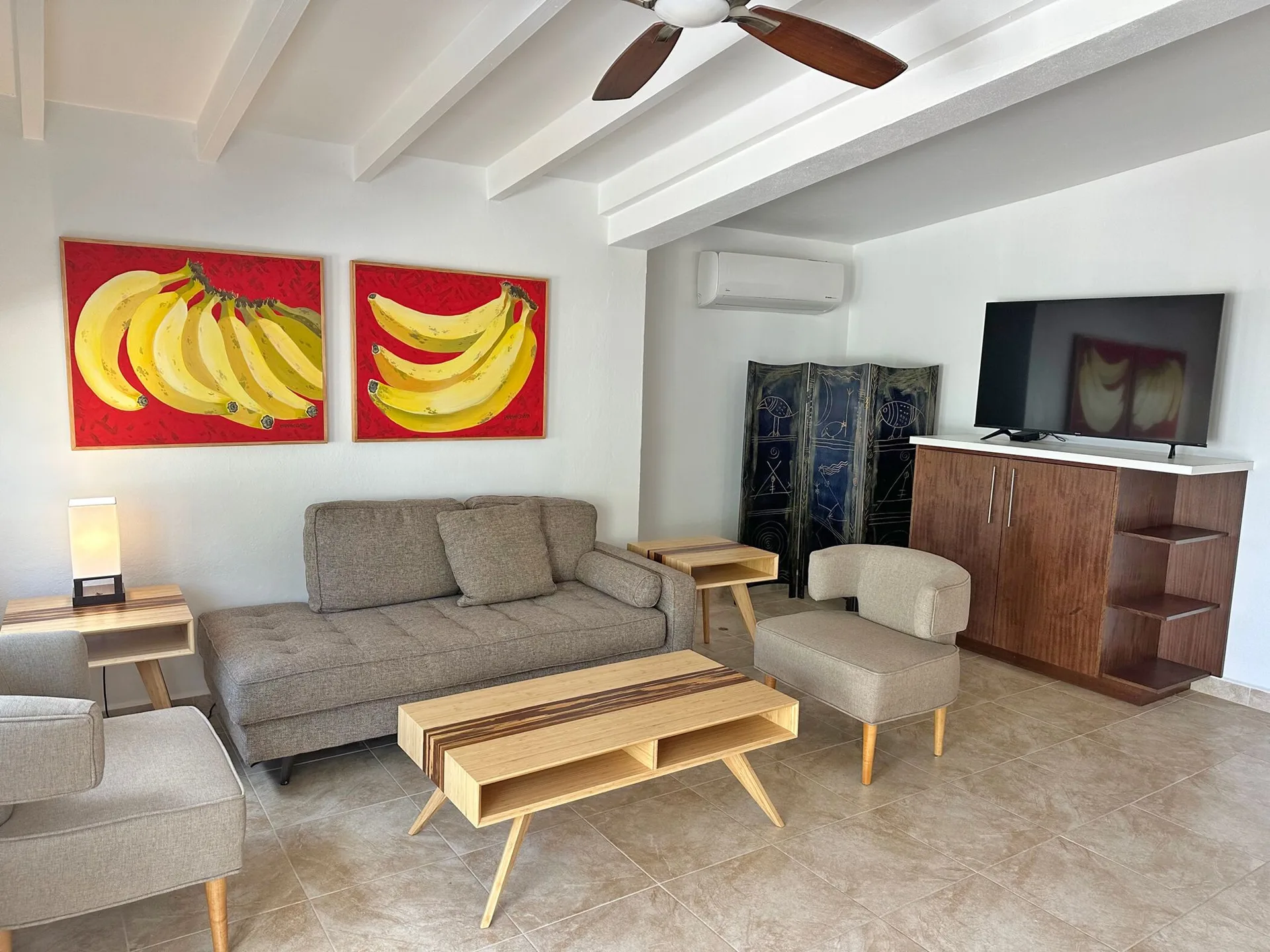 Dolphin Villa living room at Sand Castle on the Beach with sofa, chairs, TV, and banana artwork.