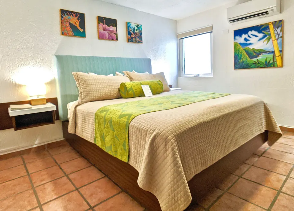 Standard Room king bed with tropical artwork at Sand Castle on the Beach.