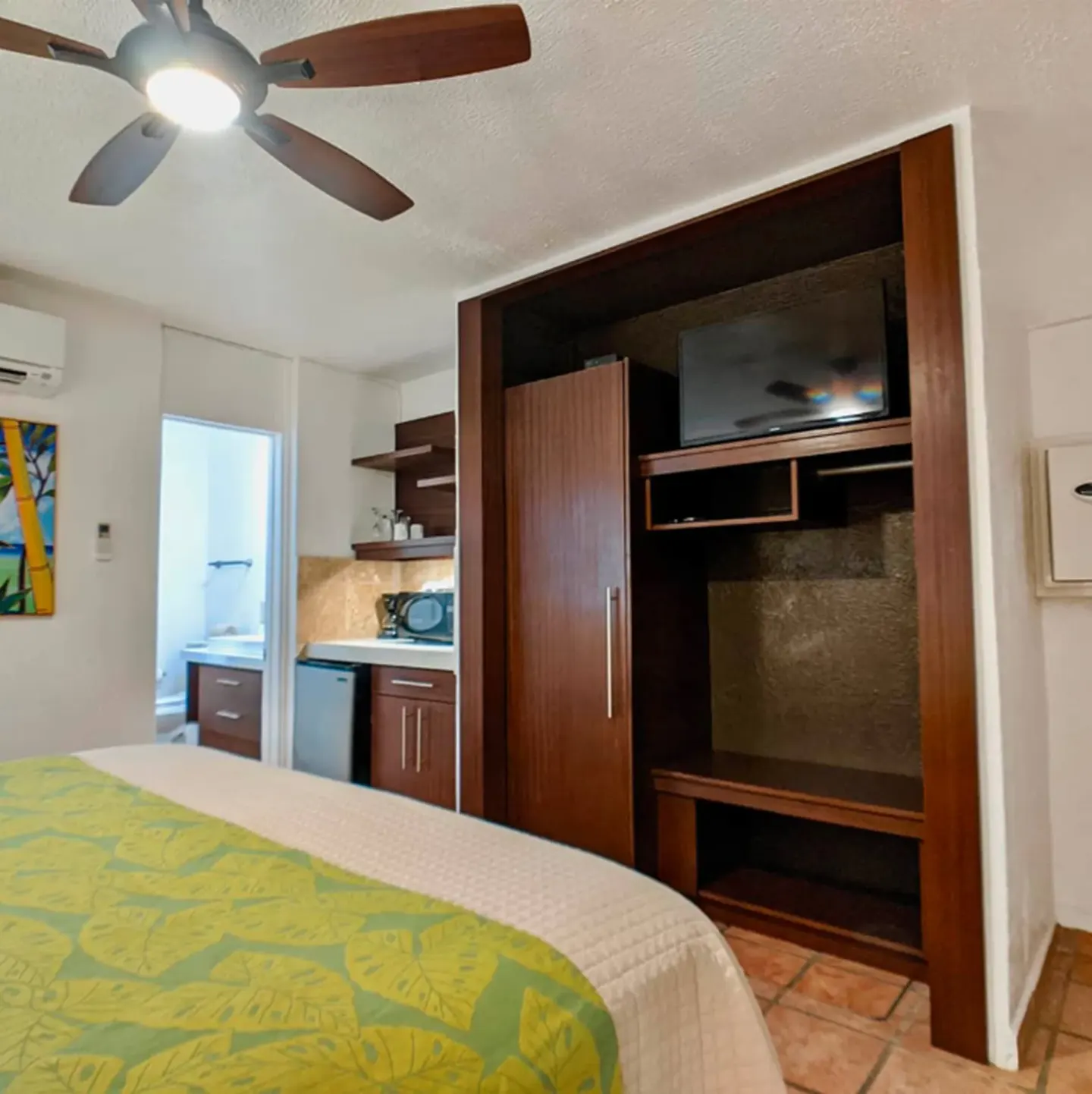 Standard Room king bed beside built-in closet and TV at Sand Castle on the Beach.