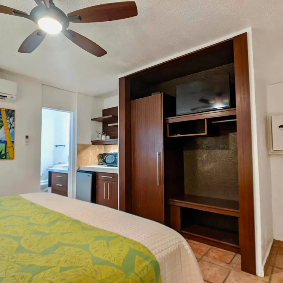Standard Room king bed beside built-in closet and TV at Sand Castle on the Beach.