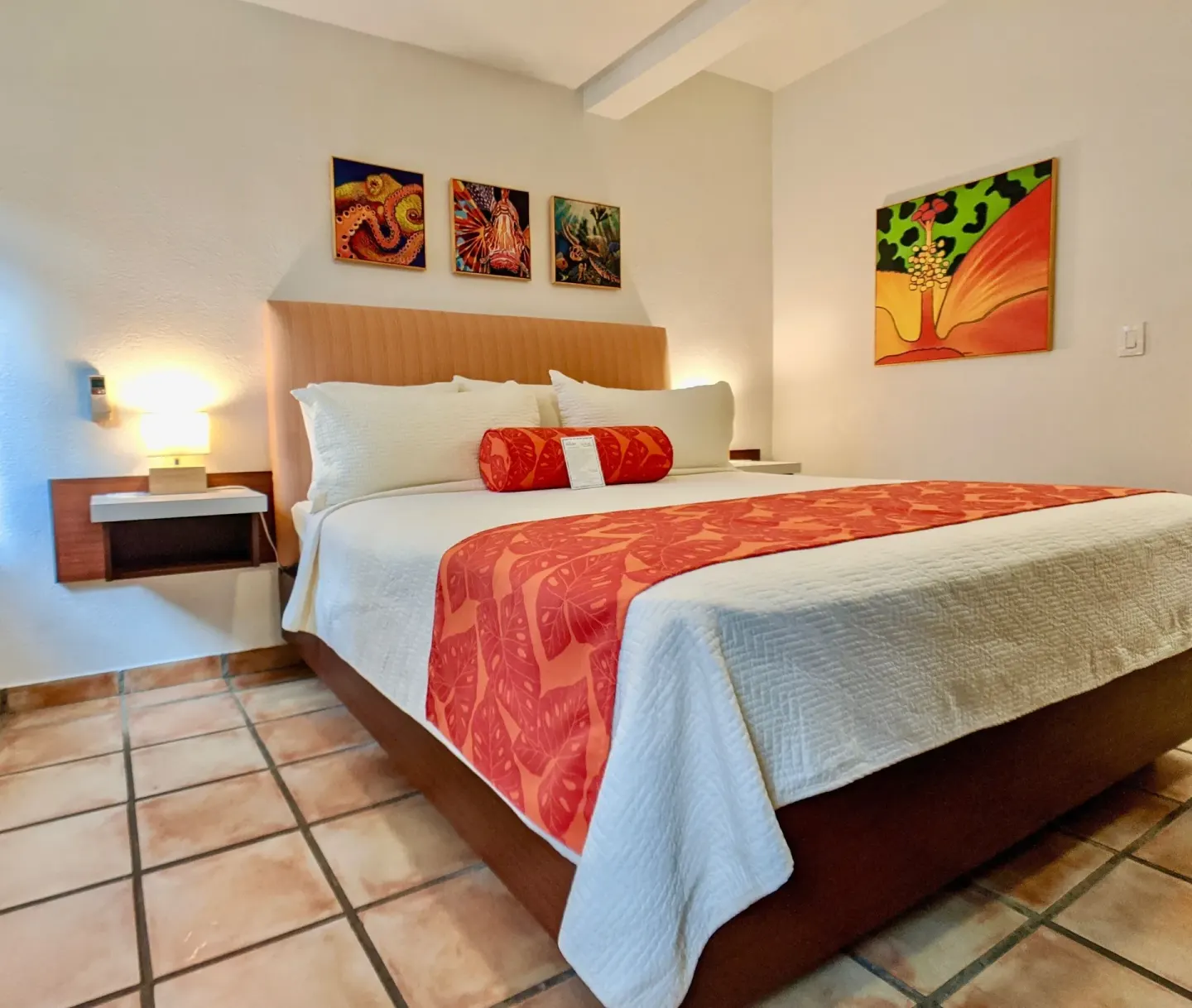 Studio Garden View room bed with red runner and wall art at Sand Castle on the Beach.