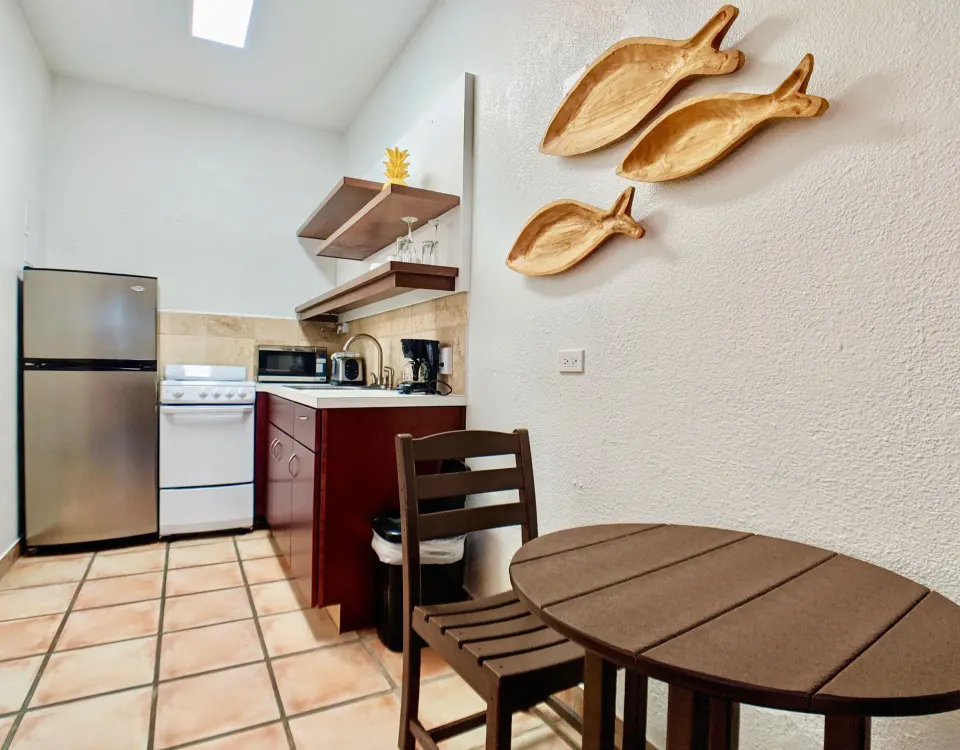 Studio Garden View kitchenette with refrigerator, stove, table, and fish wall decor at Sand Castle on the Beach.