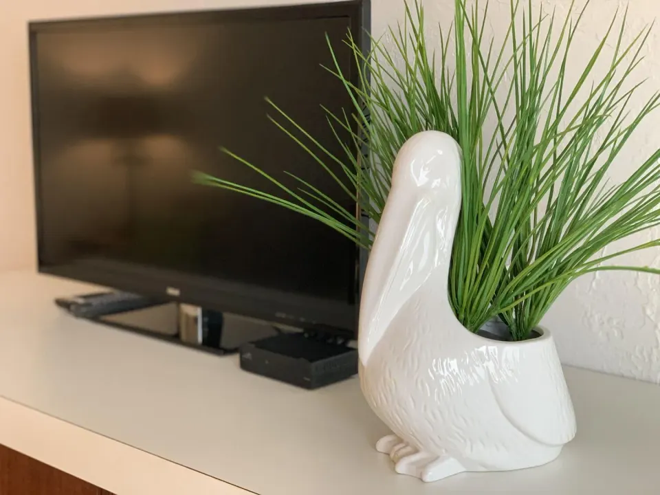 Guest room television and white pelican planter on a shelf at Sand Castle on the Beach.