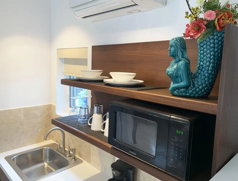 Studio kitchen corner with sink, microwave, dishes, and wall air unit at Sand Castle on the Beach.