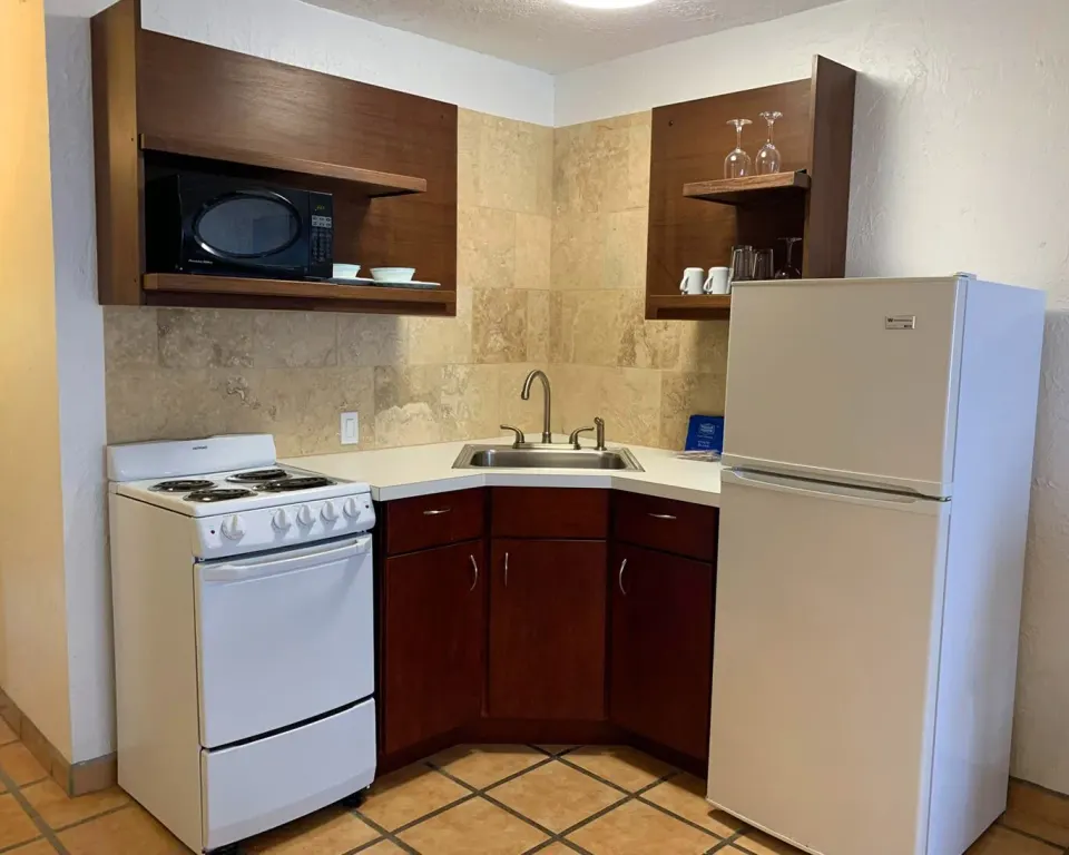 Studio kitchen with stove, sink, microwave, and refrigerator at Sand Castle on the Beach.