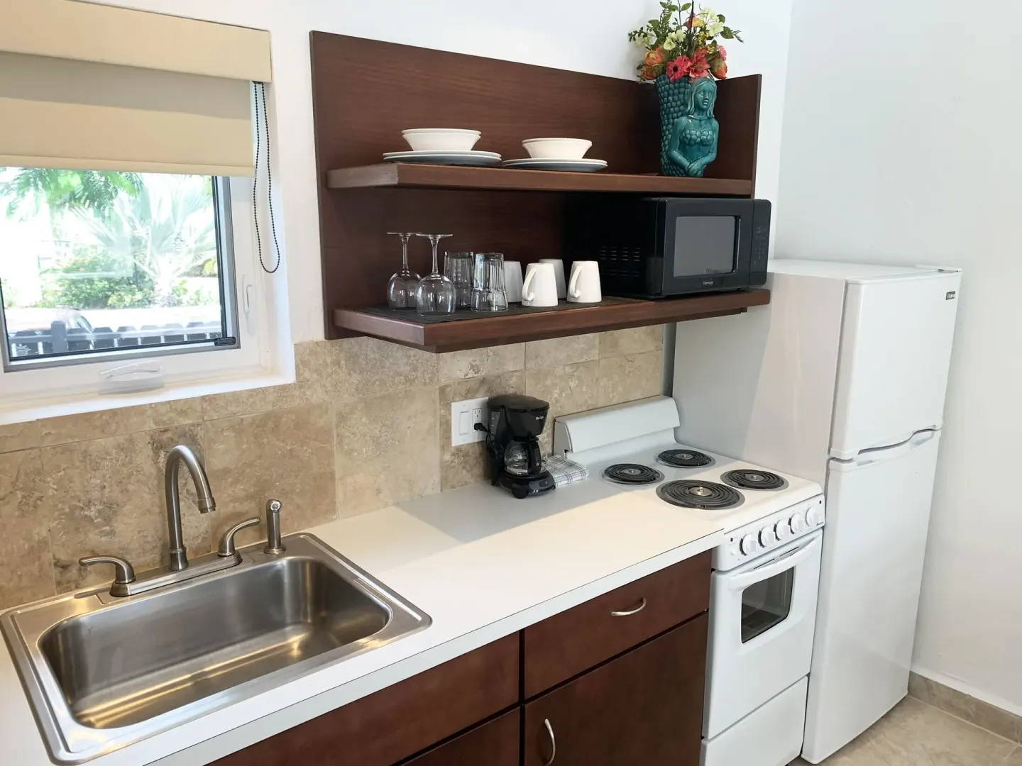 Studio kitchen with window, sink, cooktop, coffee maker, and refrigerator at Sand Castle on the Beach.