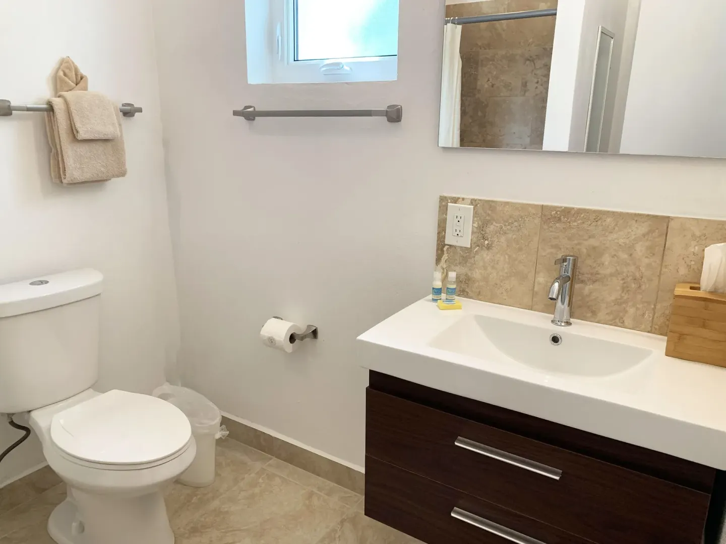 Studio bathroom at Sand Castle on the Beach with toilet, vanity, mirror, towels, and bath amenities.