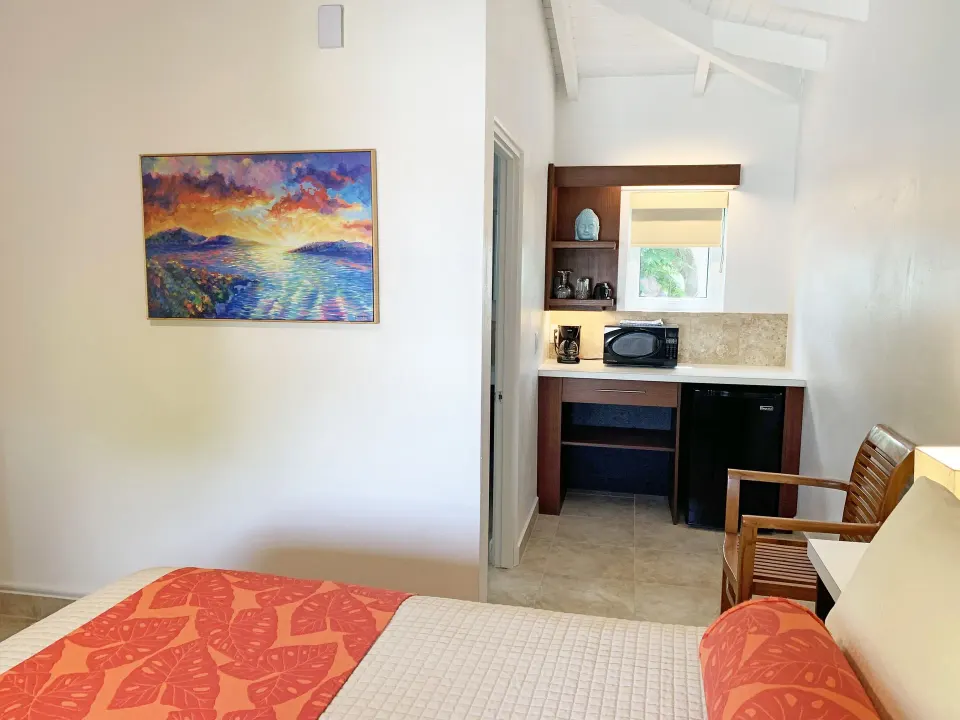 Studio bed and kitchenette area with chair and wall art at Sand Castle on the Beach.