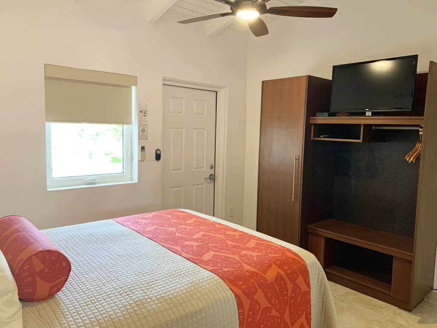 Studio king bed, window, entry door, wardrobe, and TV at Sand Castle on the Beach.
