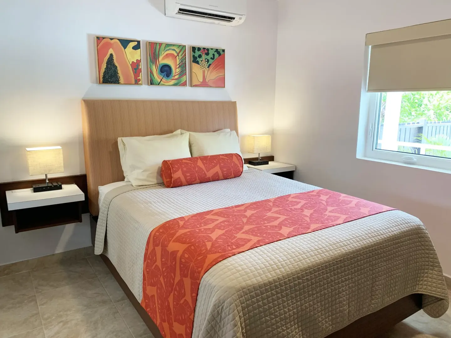 Studio king bed beside a window with roller shade at Sand Castle on the Beach.