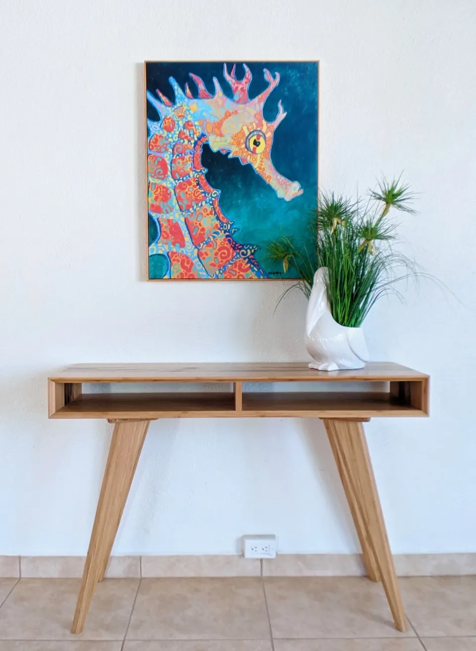 Console table with seahorse artwork and a decorative plant at Sand Castle on the Beach.