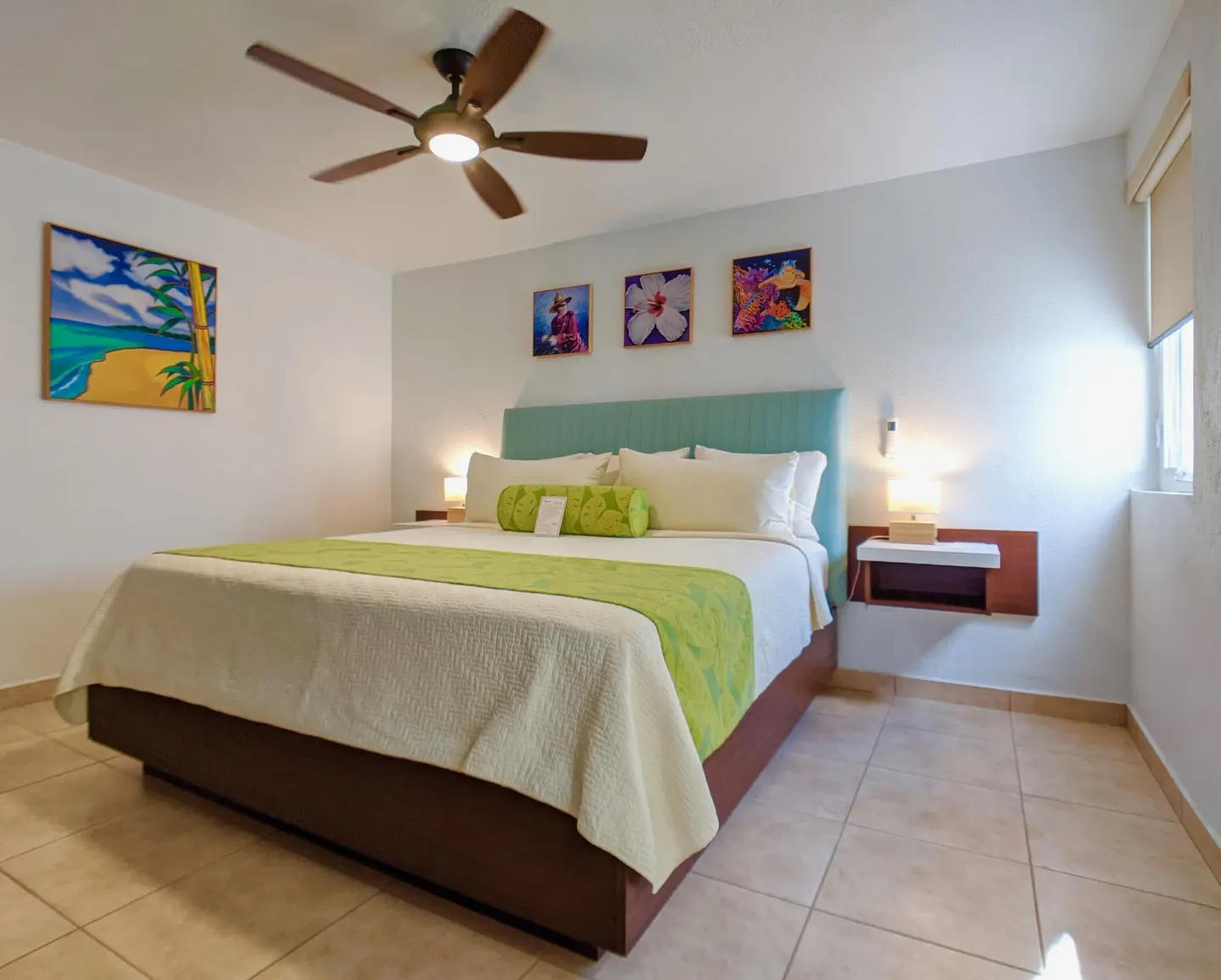 Bedroom with a king bed, turquoise headboard, and island art at Sand Castle on the Beach.