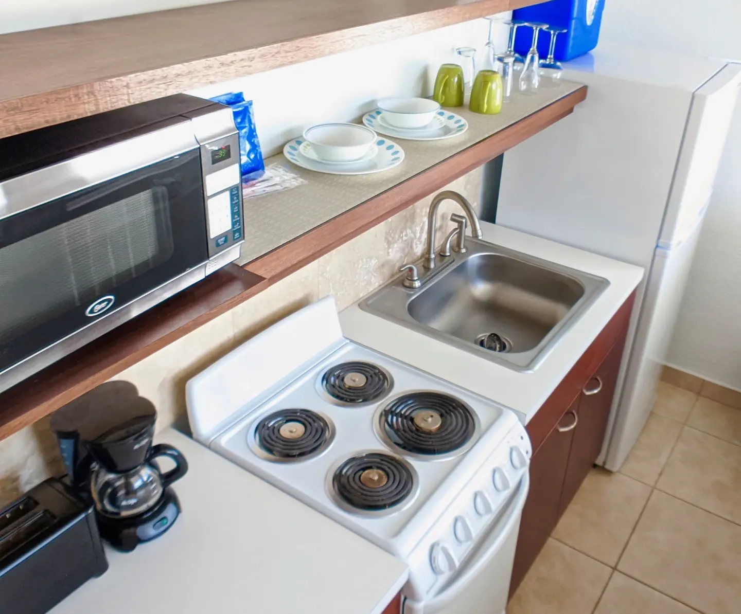 Suite kitchenette with stove, sink, microwave, coffee maker, and dishes at Sand Castle on the Beach.