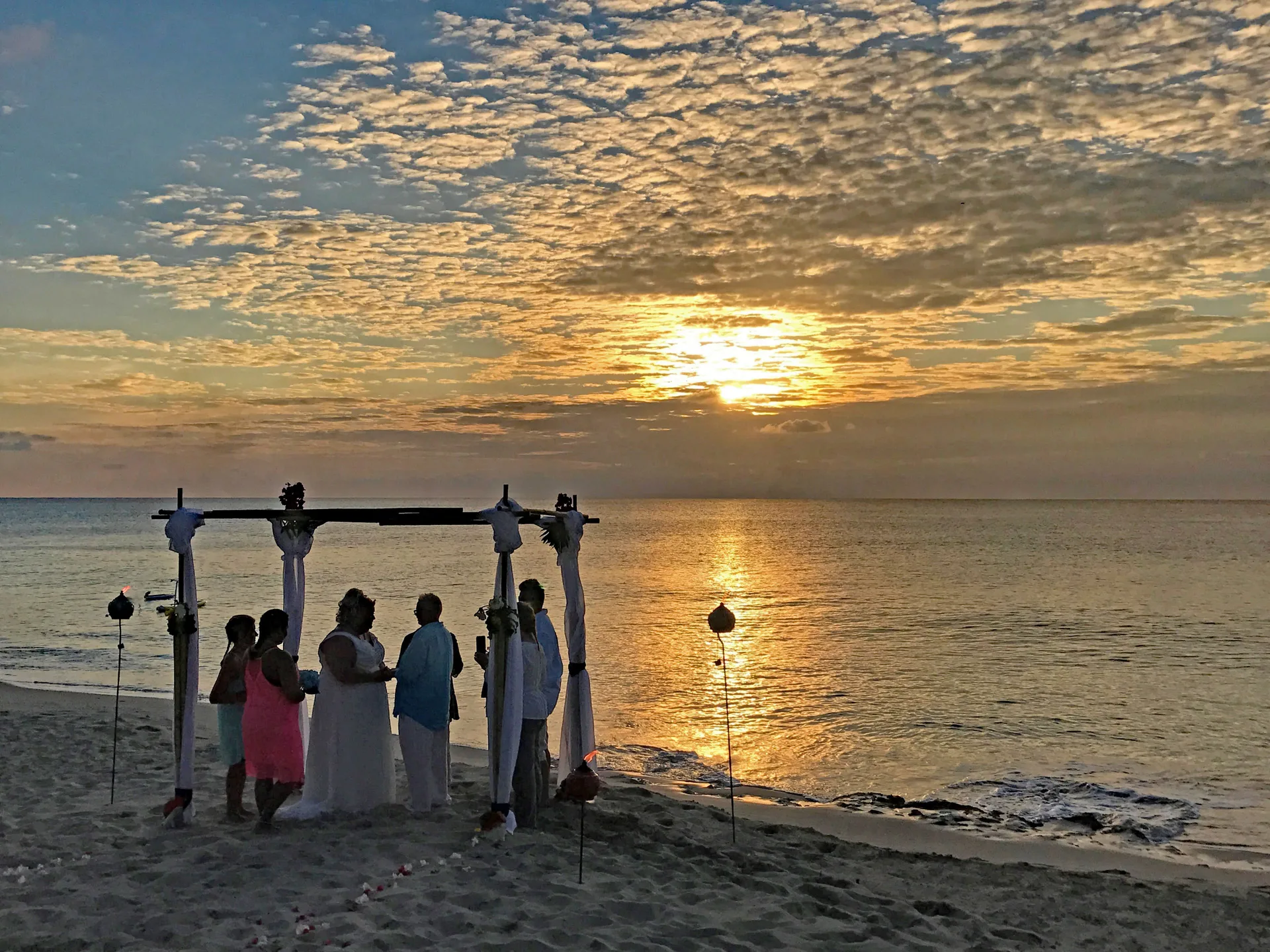 Beach wedding ceremony at sunset at Sand Castle on the Beach.