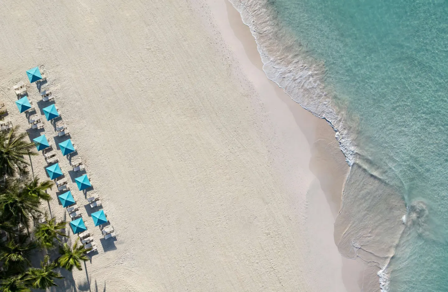 Aerial view of white sand beach with turquoise umbrellas at Sandals Barbados.