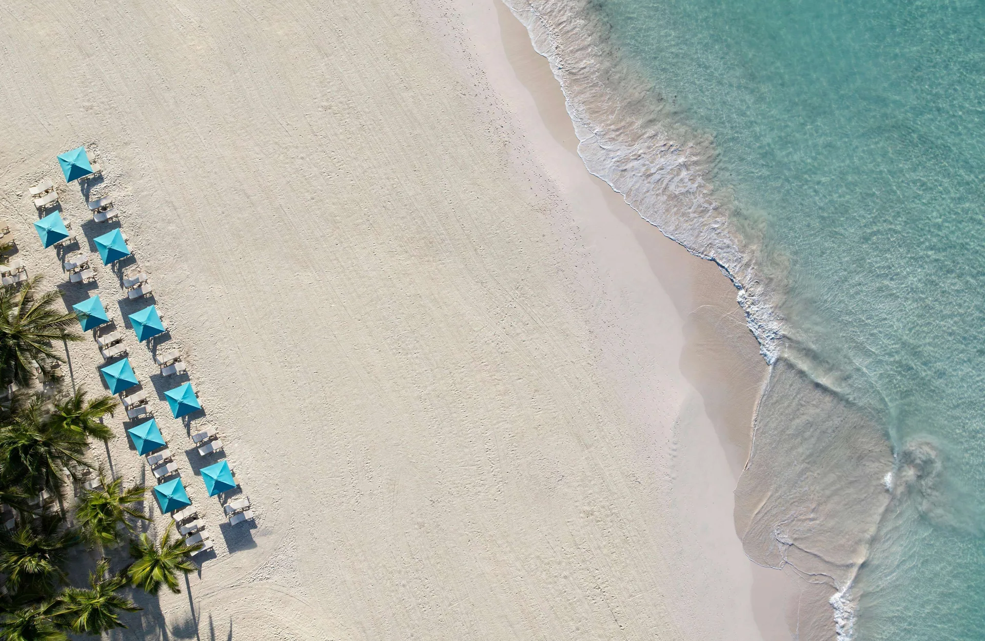 Aerial view of white sand beach with turquoise umbrellas at Sandals Barbados.