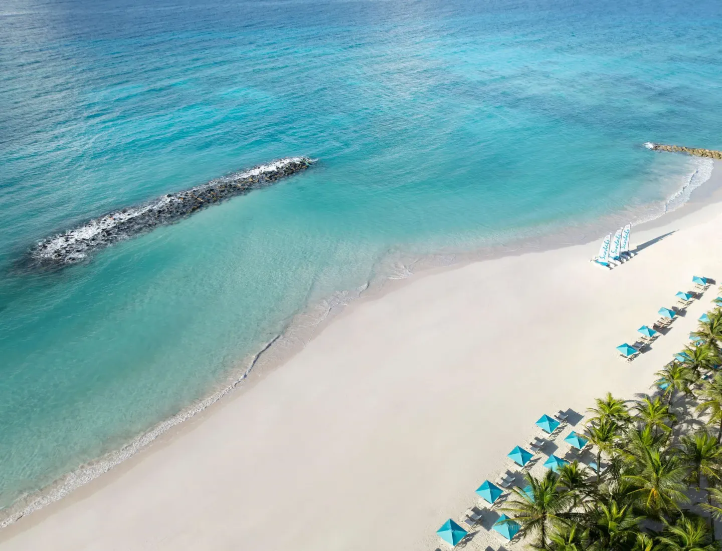 Aerial beach view with clear turquoise water and loungers at Sandals Barbados.
