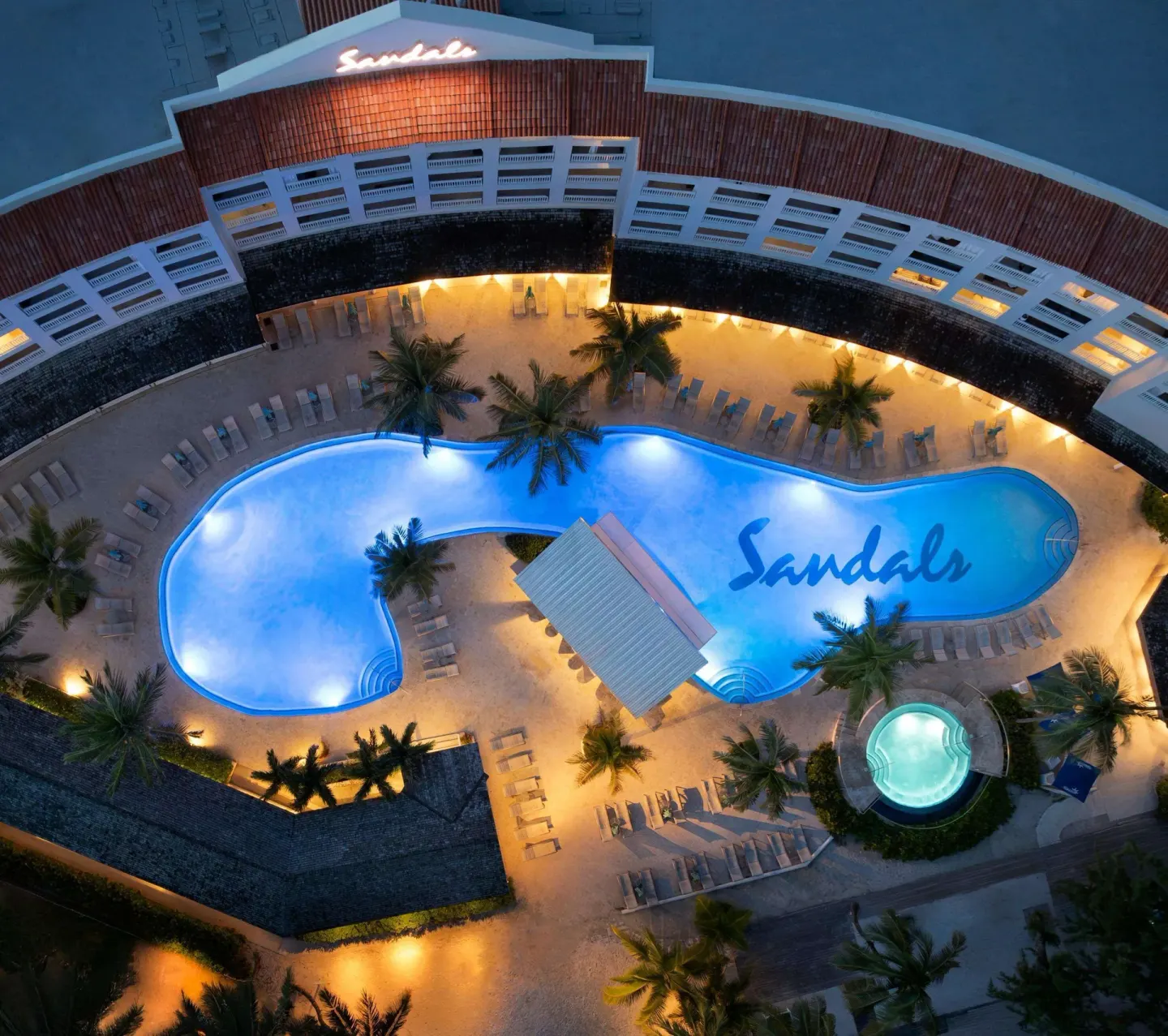 Aerial evening view of the illuminated main pool at Sandals Barbados.