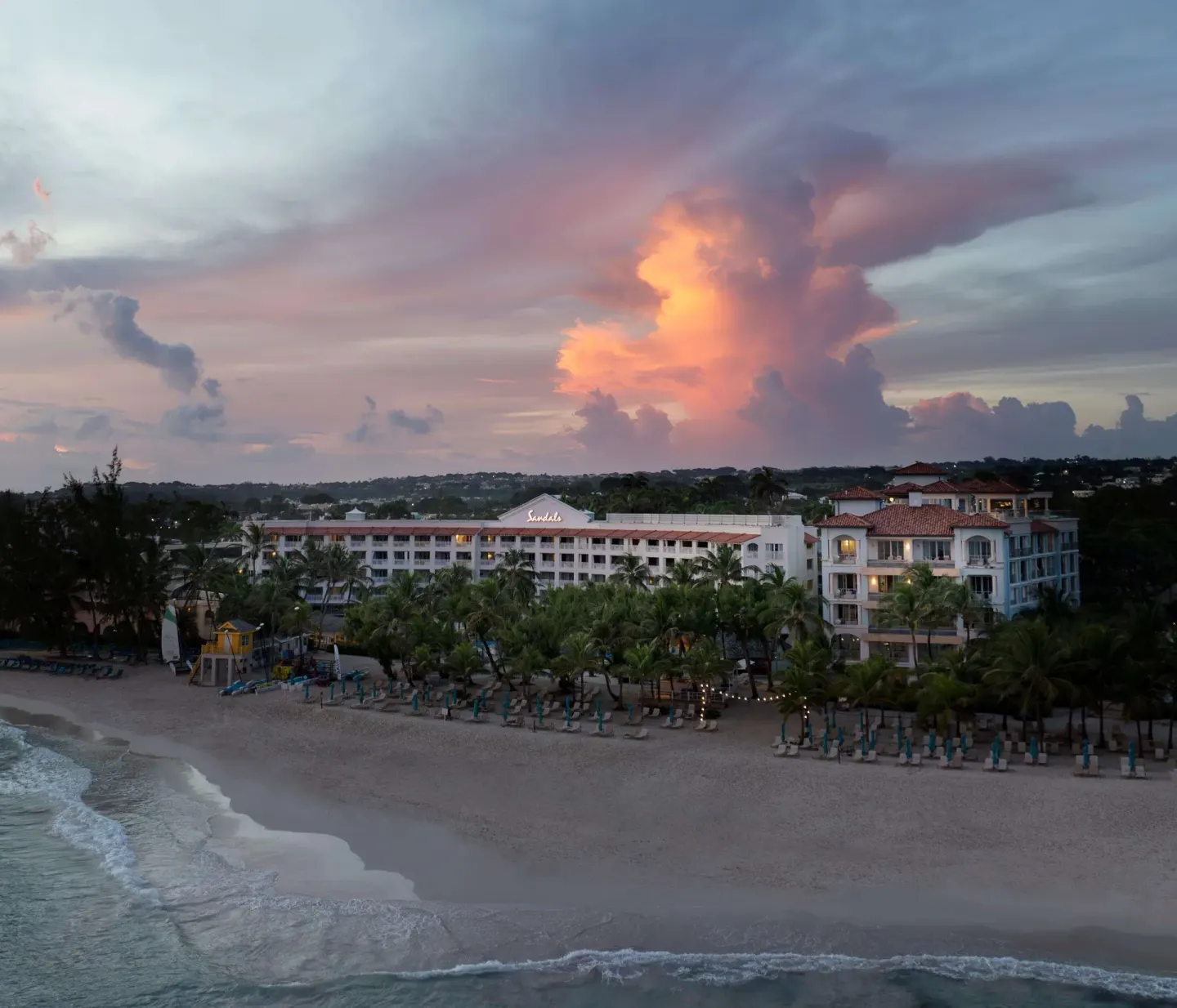 Resort buildings and beach at sunset with dramatic clouds at Sandals Barbados.