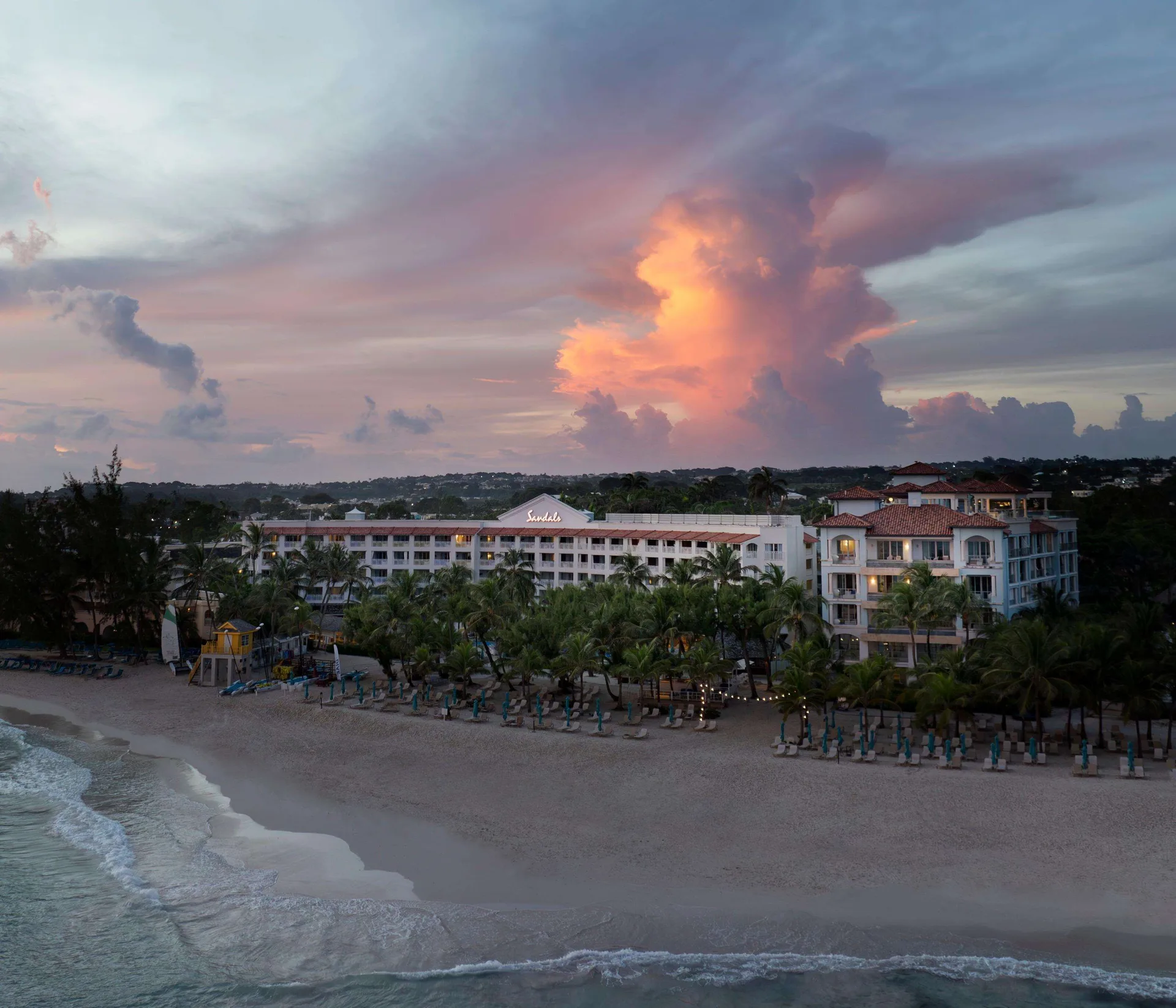 Resort buildings and beach at sunset with dramatic clouds at Sandals Barbados.