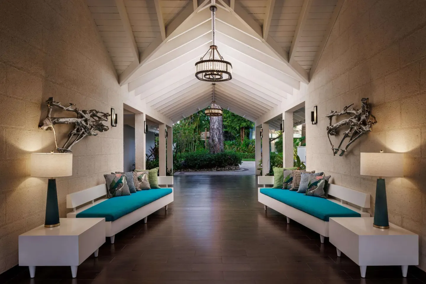 Covered resort walkway with teal cushioned benches at Sandals Barbados.