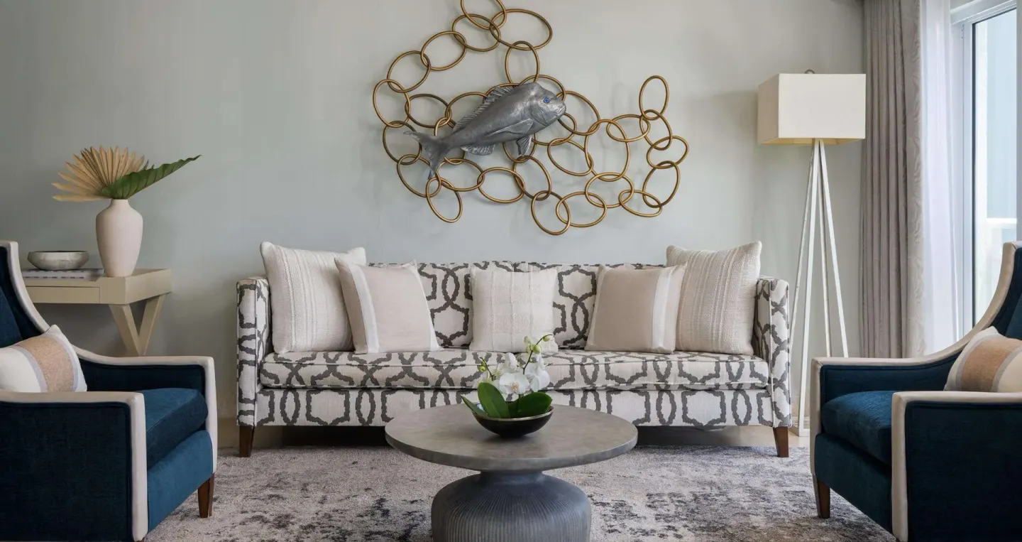 Guest room sitting area with sofa, blue chairs, and fish wall art at Sandals Barbados.