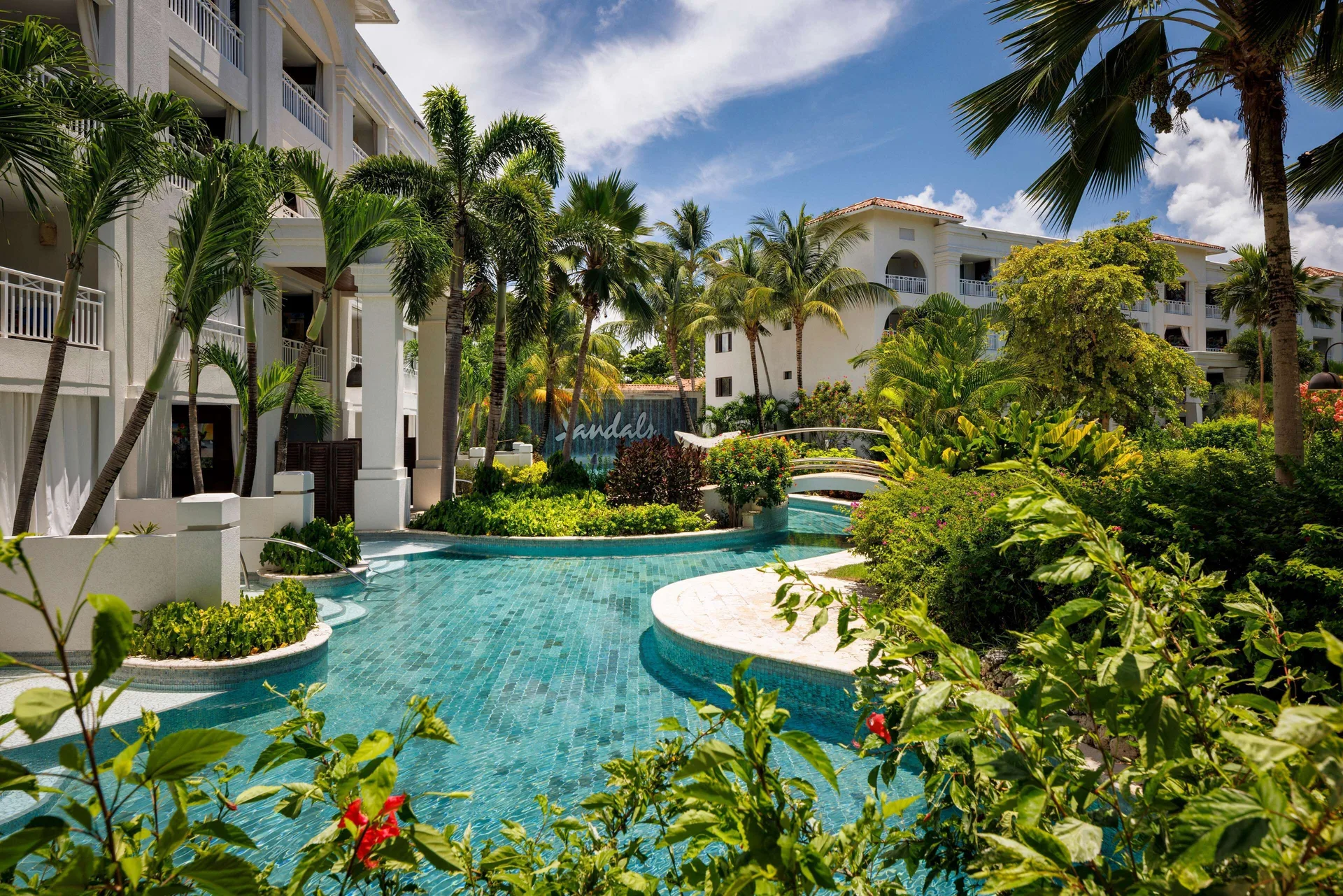 Lagoon pool, palms, and white guest buildings at Sandals Barbados.