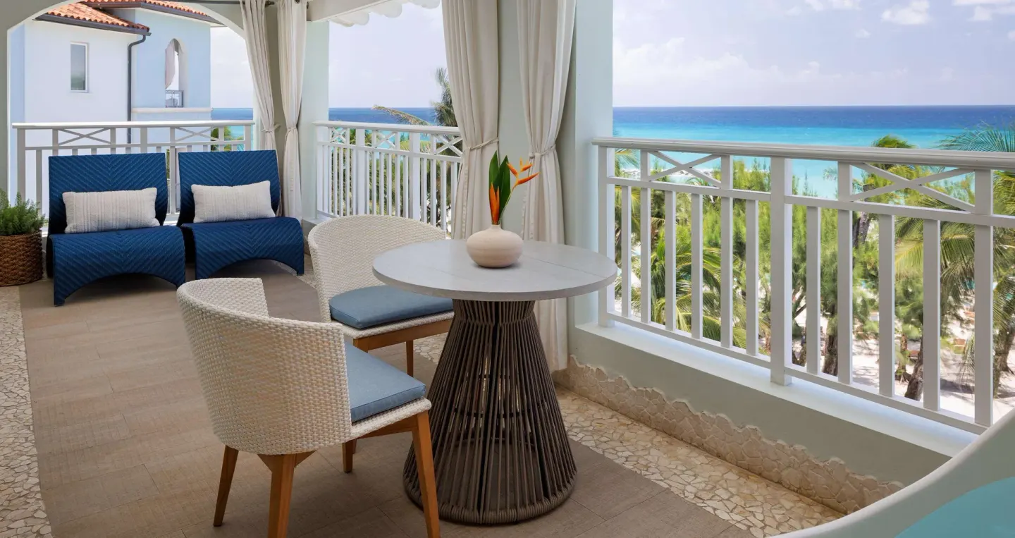 Ocean view balcony with lounge chairs and table seating at Sandals Barbados.