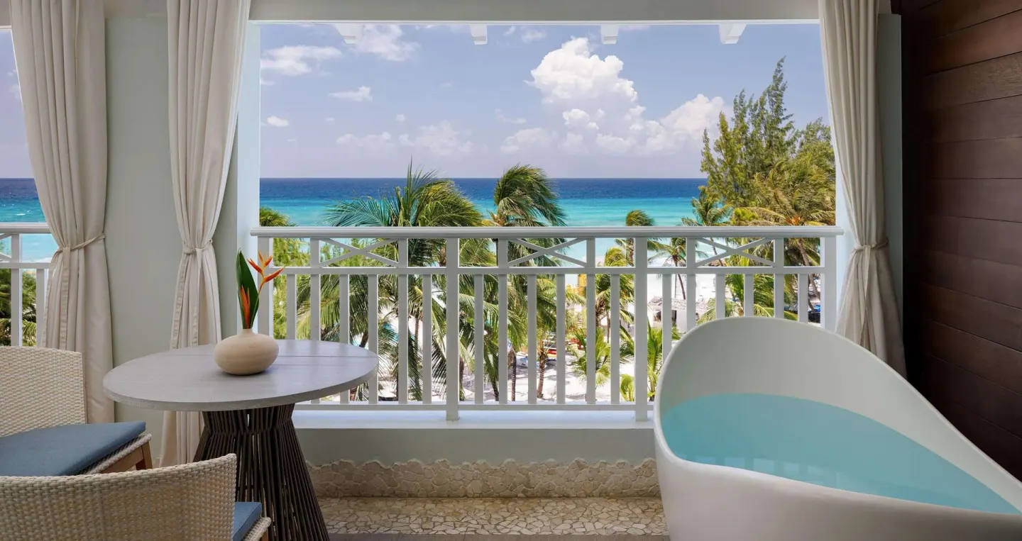 Ocean-view balcony with soaking tub and seating at Sandals Barbados.