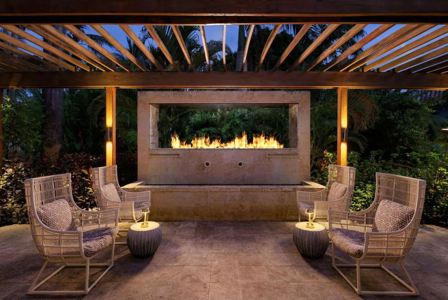 Covered outdoor lounge with wicker chairs and a fireplace at Sandals Barbados.