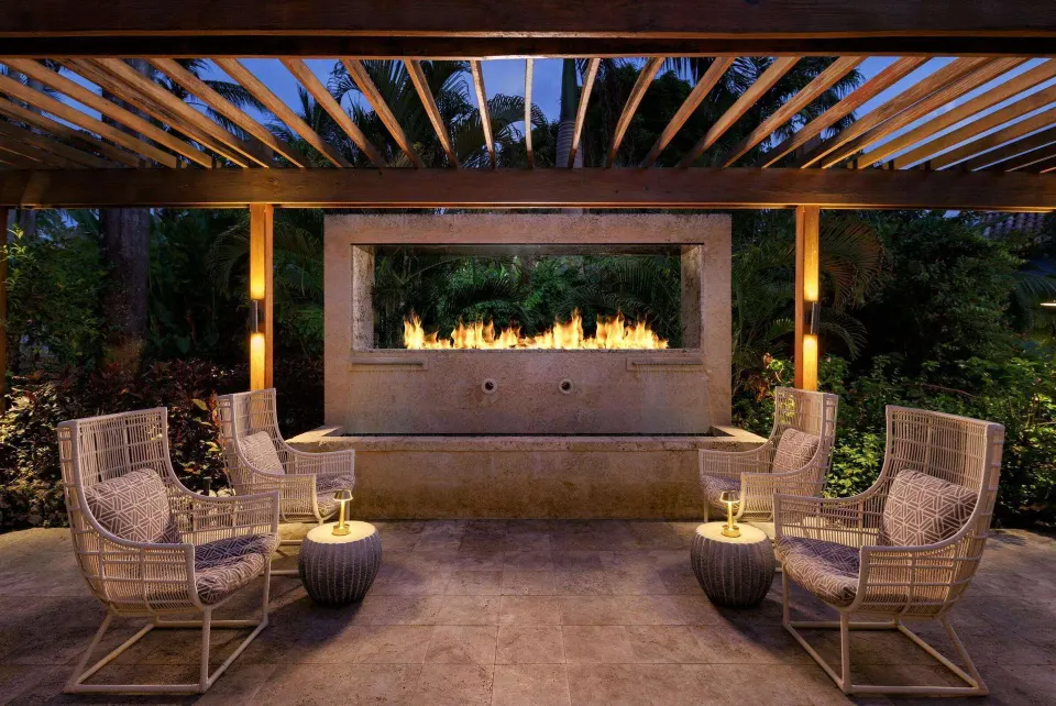 Covered outdoor lounge with wicker chairs and a fireplace at Sandals Barbados.