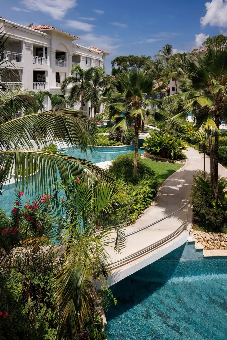 Palm-lined walkway and lagoon pool beside guest buildings at Sandals Barbados.