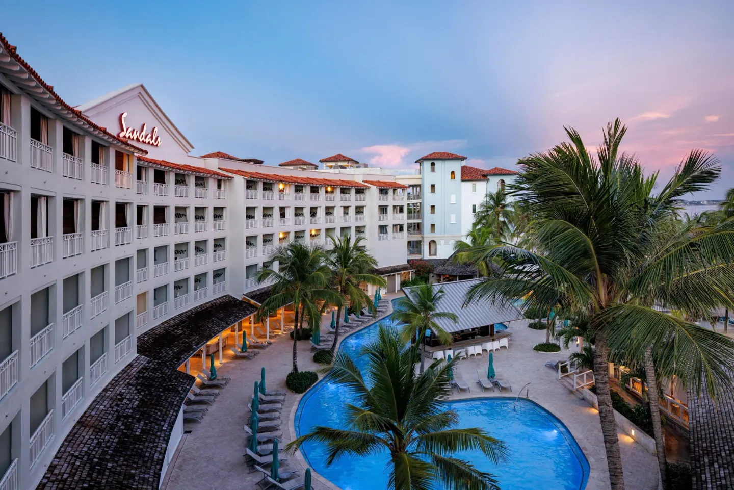 Pool courtyard with palm trees and white resort buildings at Sandals Barbados.